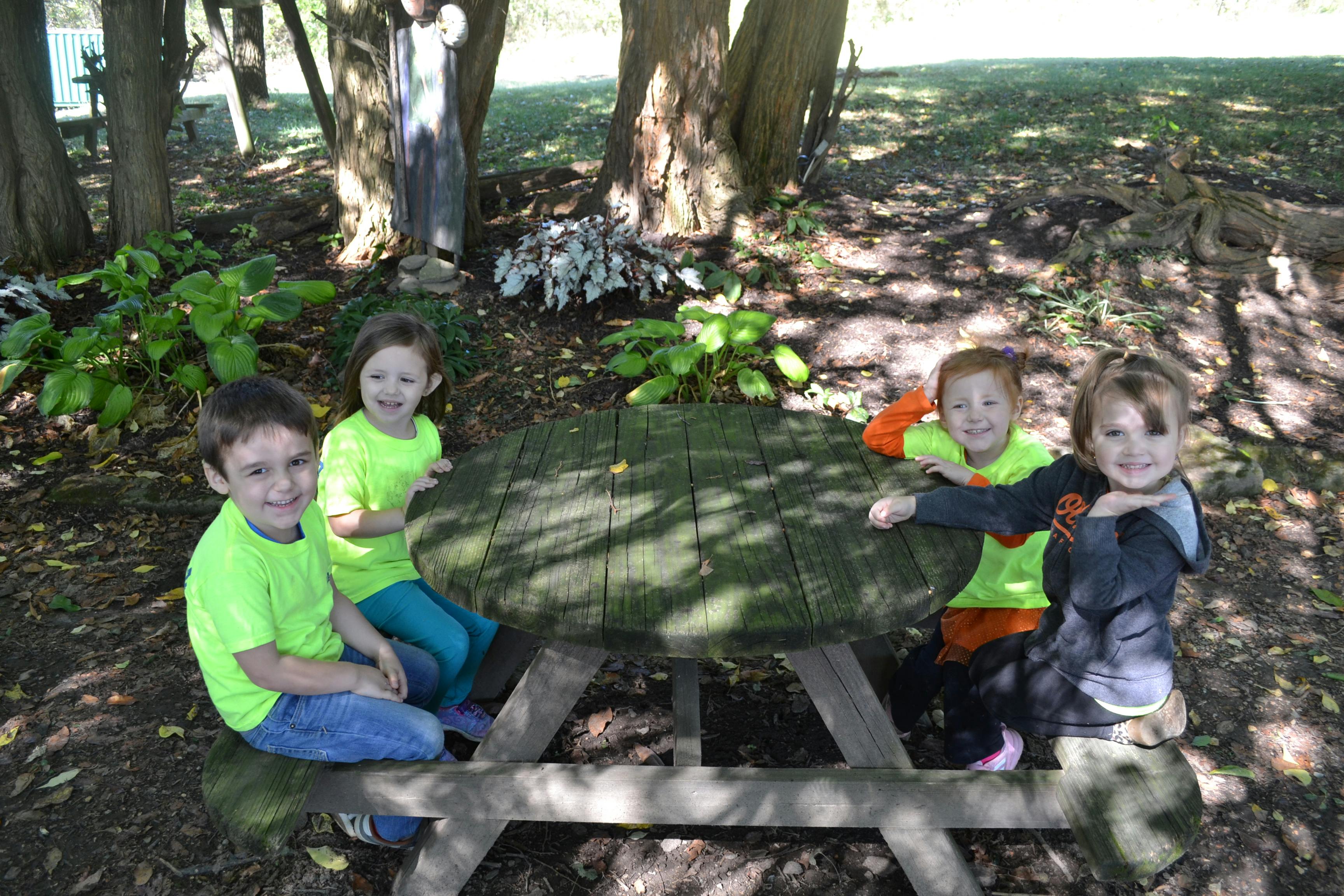 Four children sitting at a picnic table outdoors