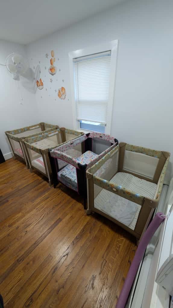 Four portable cribs in a row on a wooden floor