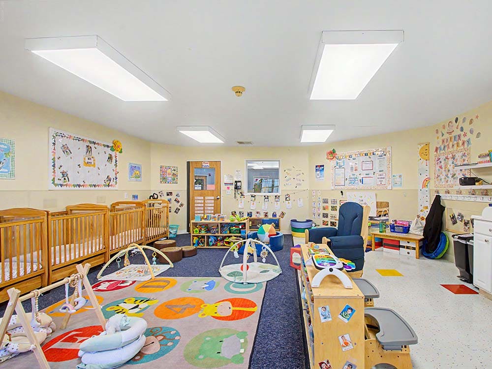 Cribs and playmats in a bright daycare room