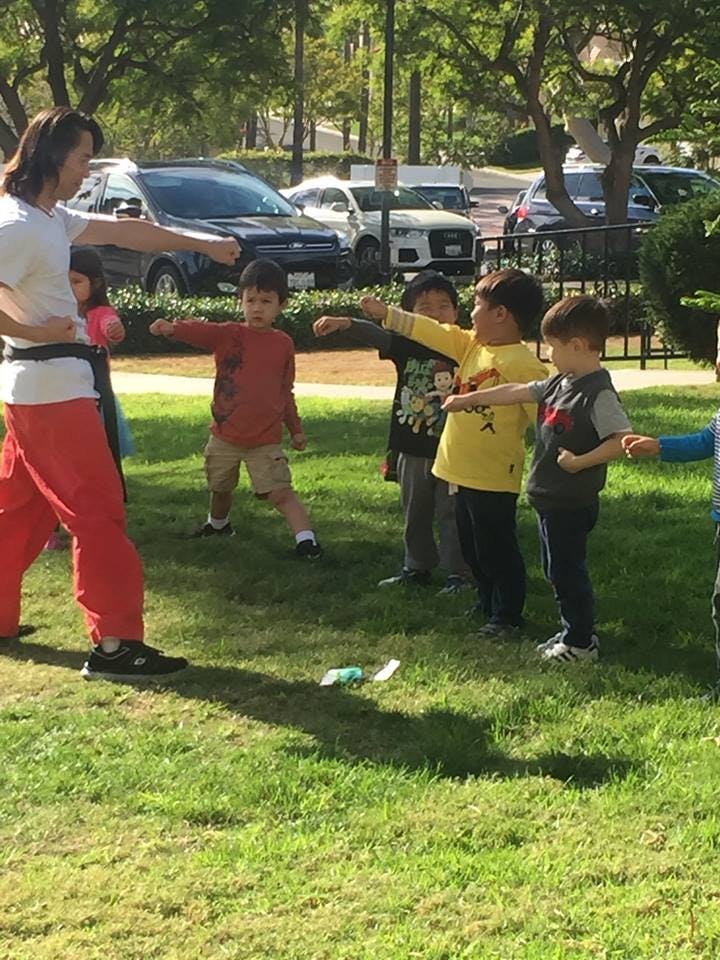 Person and children practicing martial arts stances outdoors