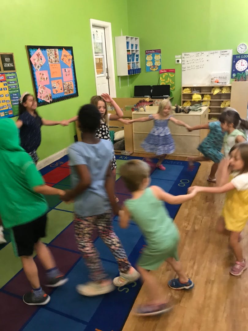 Children holding hands in a circle in a classroom