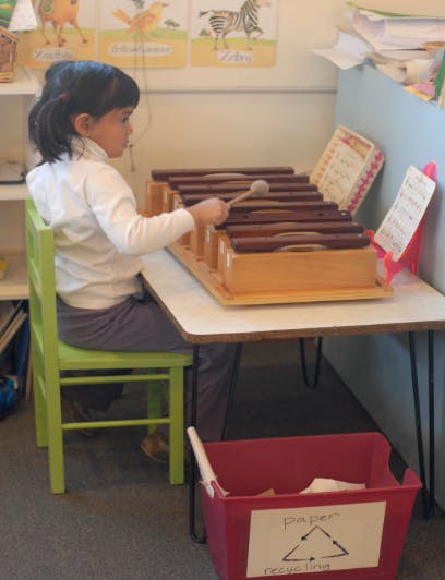 Child playing a xylophone at a table