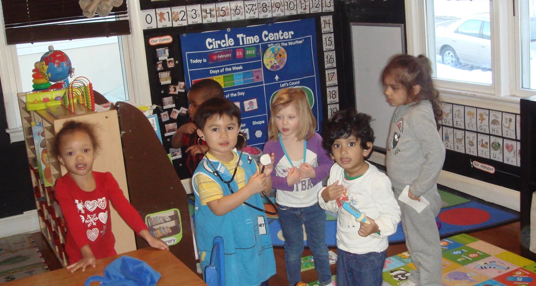 Five children playing in a classroom