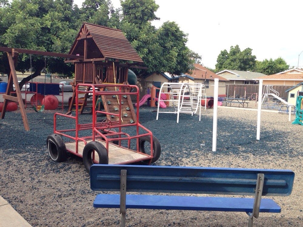 Playground with swings, climbing structure, and a red play vehicle