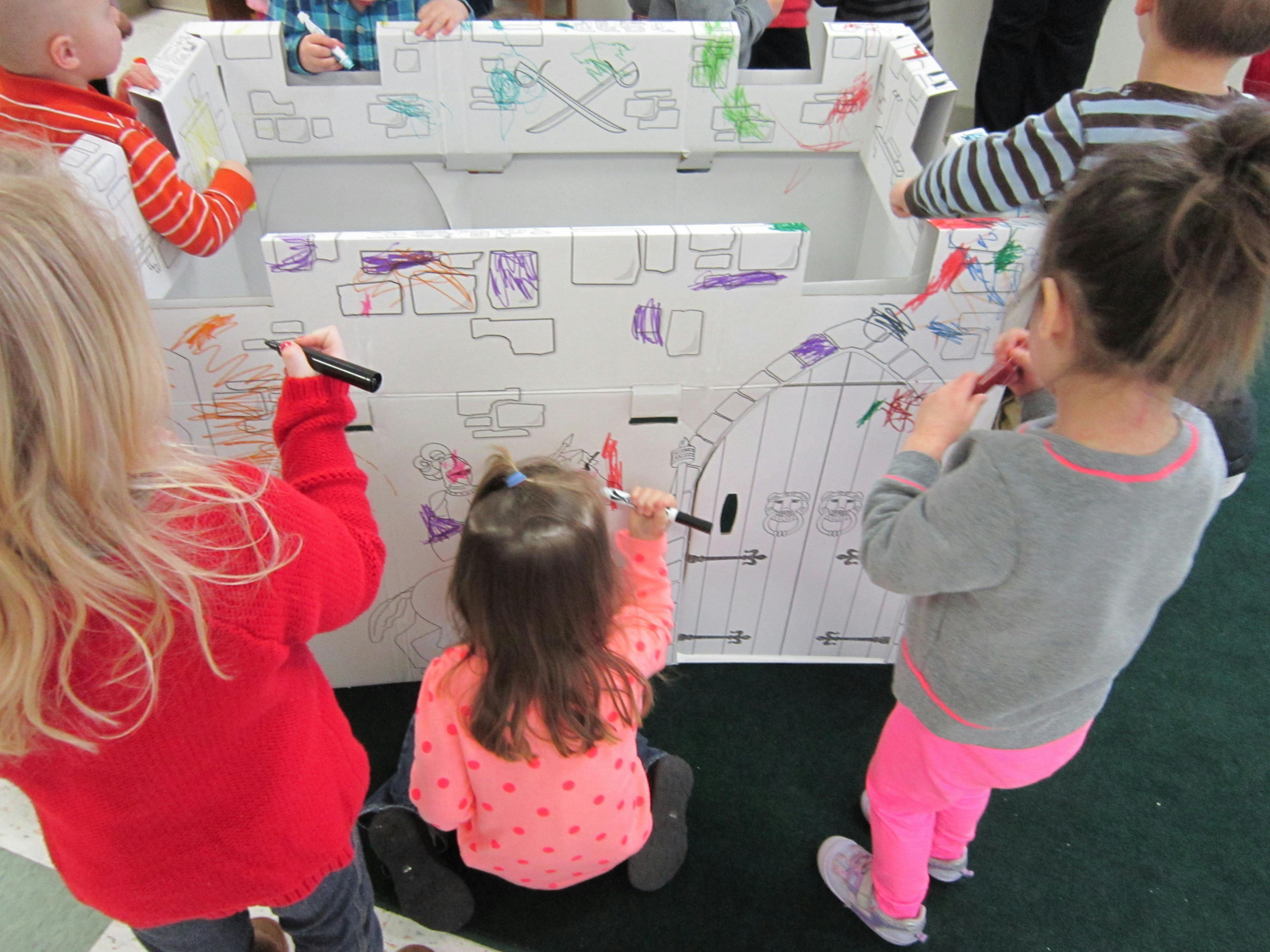 Children drawing on a large cardboard structure