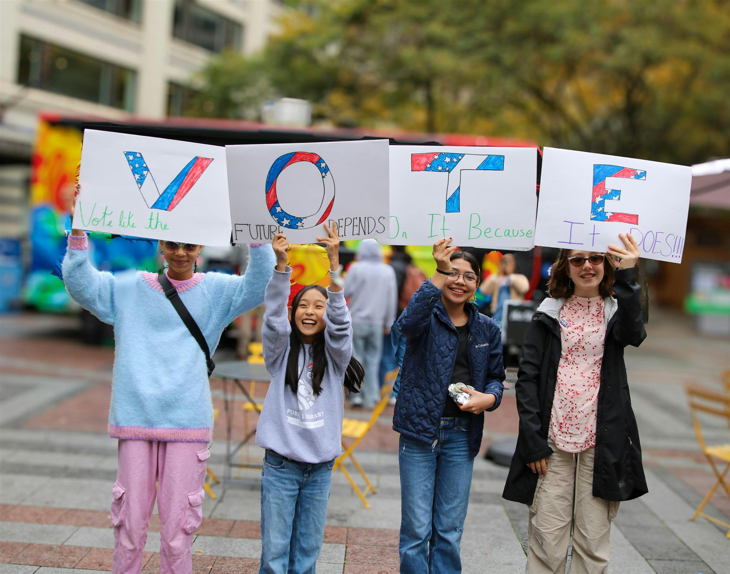 Four young people holding up signs that spell out "VOTE"