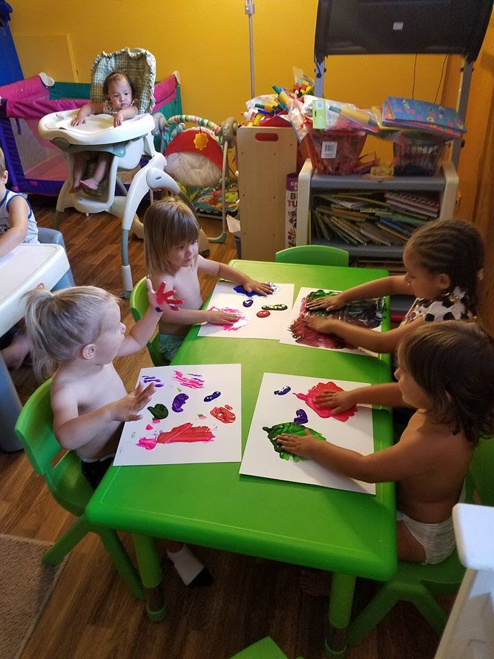 Children finger painting at a green table