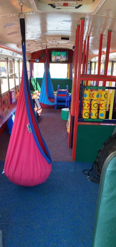 Interior of a bus converted into a play area with hanging fabric swings
