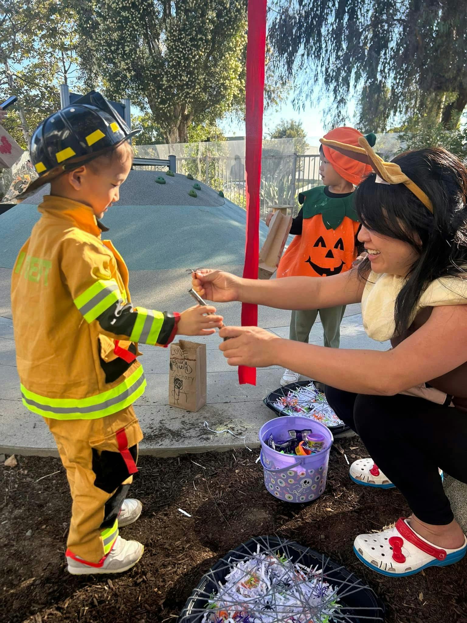 Child in firefighter costume receiving an item from a person