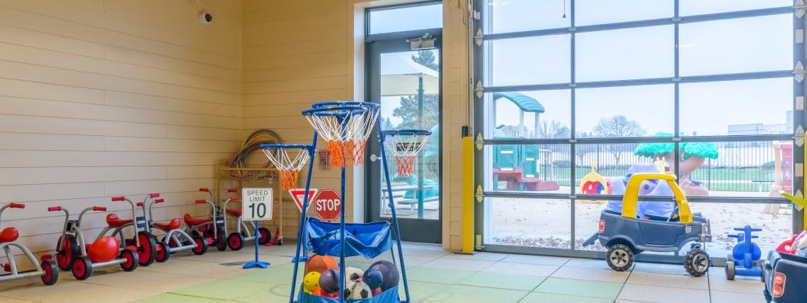 Indoor play area with tricycles, basketball hoops, and toy cars