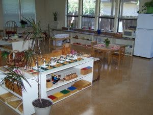 Classroom with tables, chairs, and shelves with learning materials