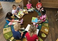 Children sitting in a circle on a rug, reading books