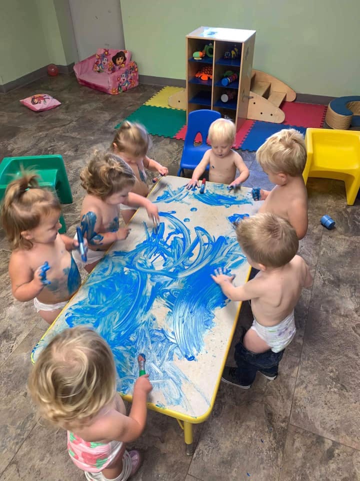 Children finger painting with blue paint at a table