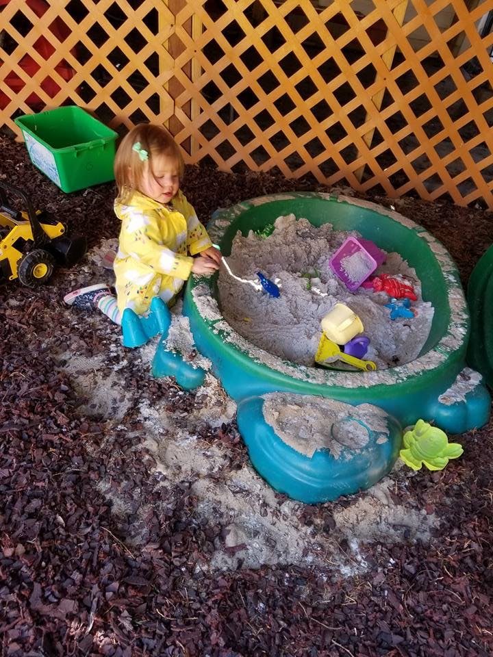 Child playing in a sandbox with a shovel