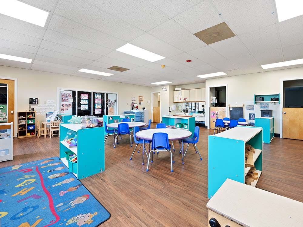 Empty classroom with small round tables and blue chairs