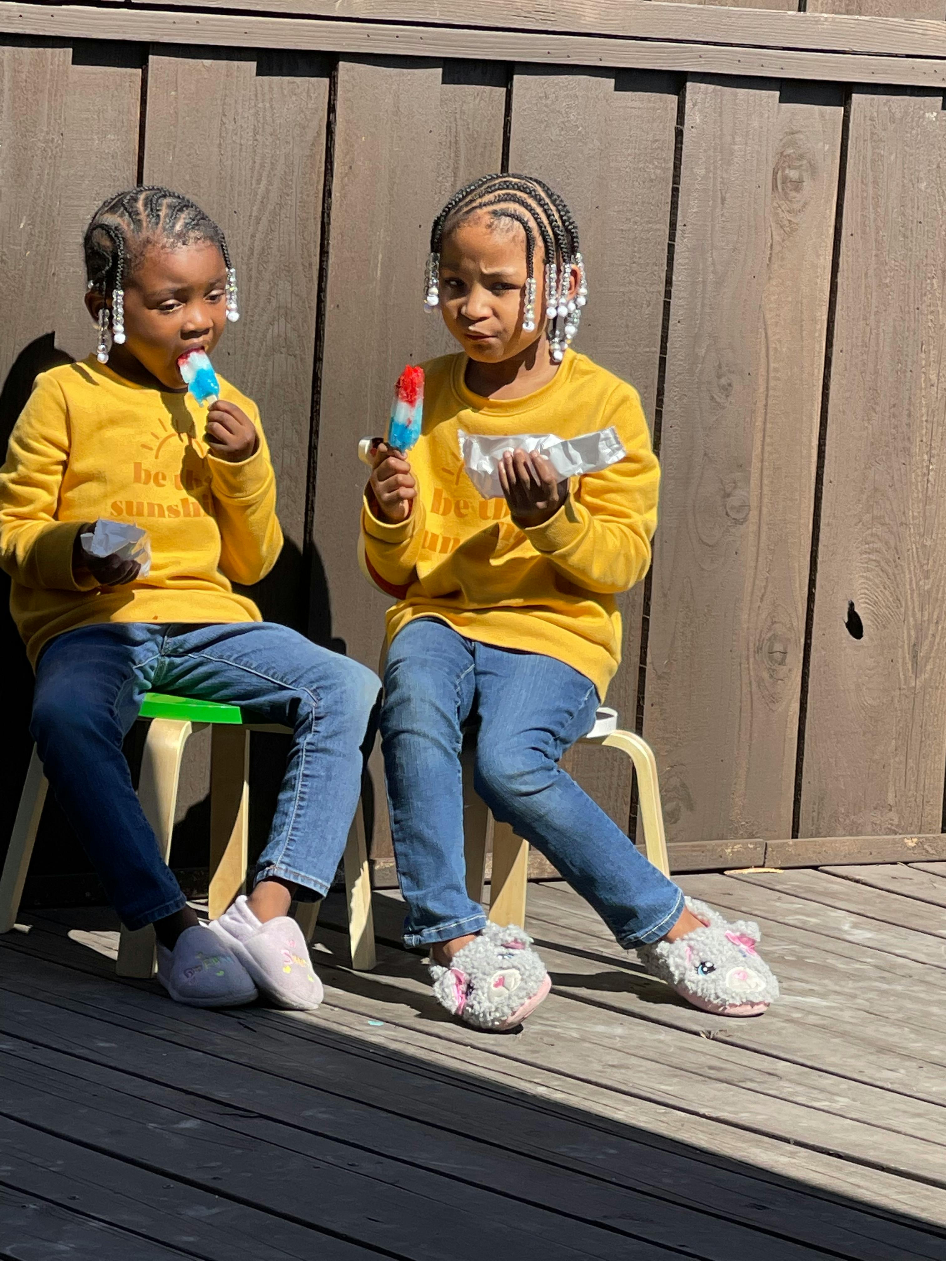 Two children sitting and eating popsicles
