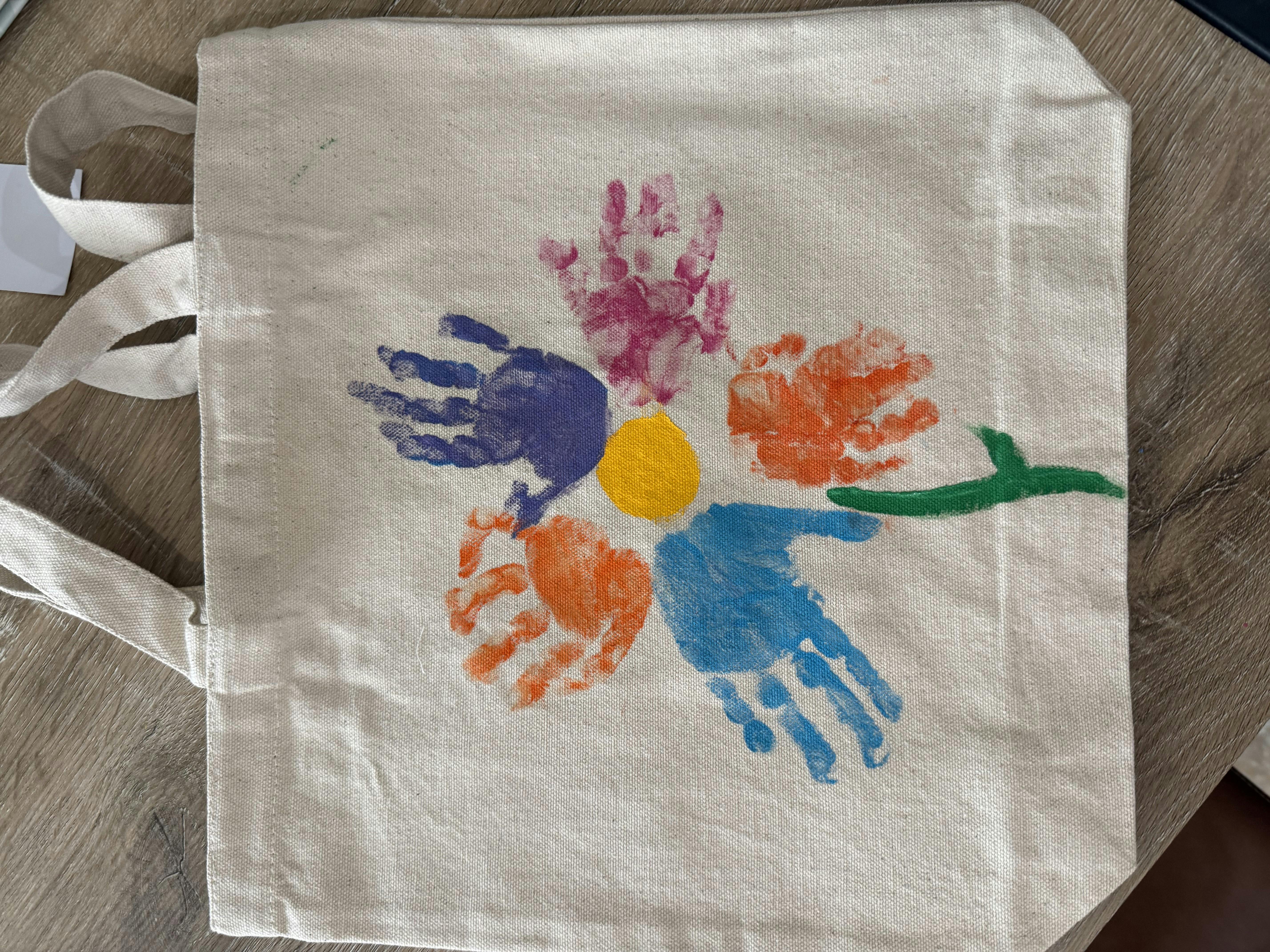 Tote bag with colorful handprints arranged in a flower shape