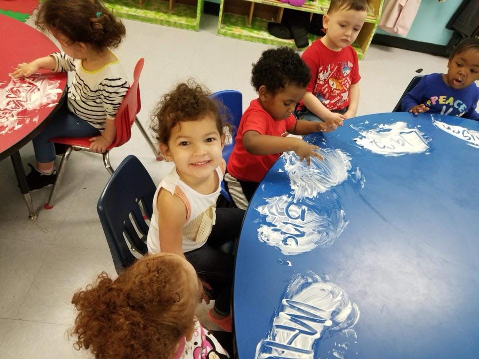 Children doing an art activity at tables in a classroom