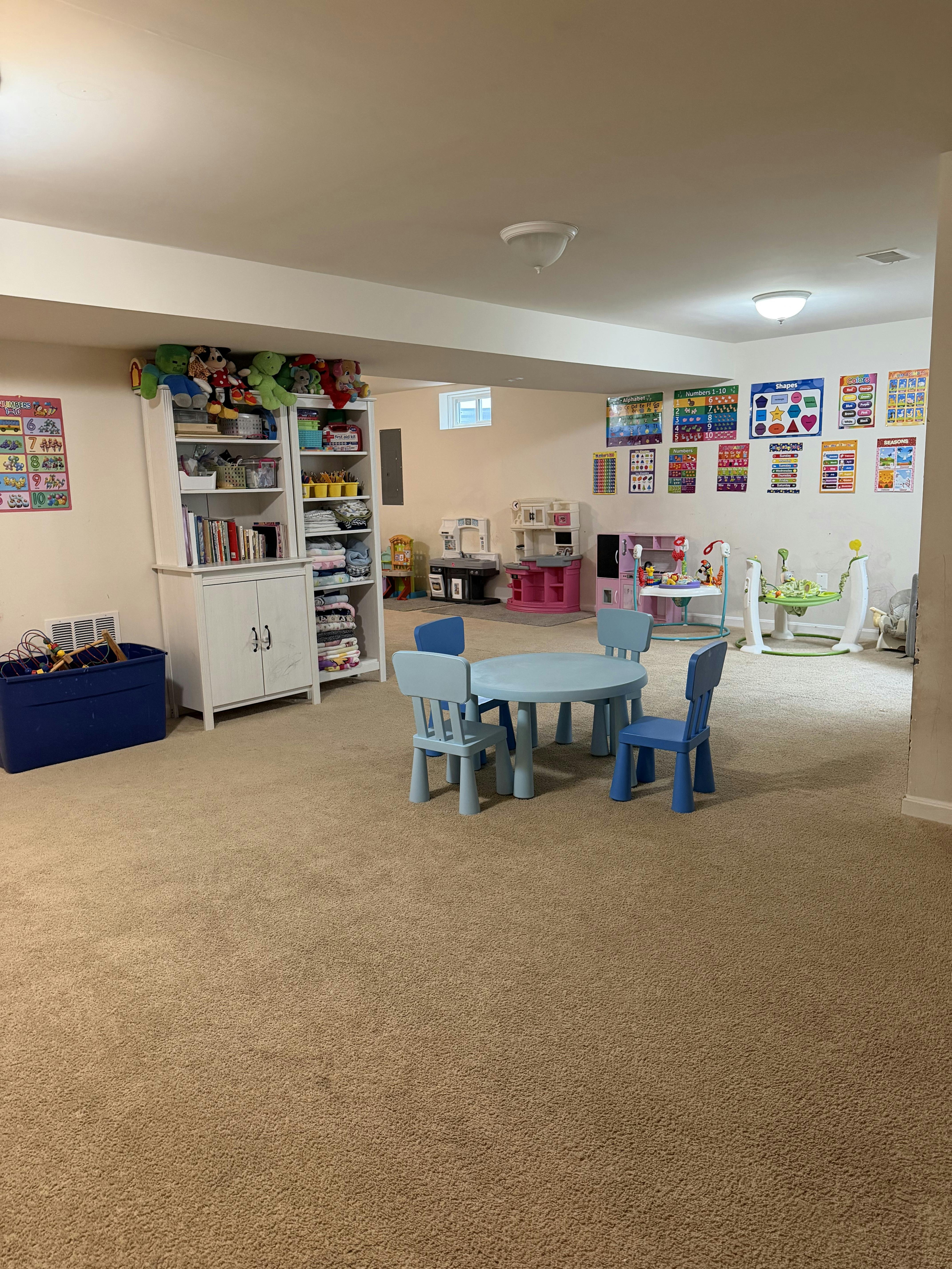 Playroom with a small table and chairs surrounded by toys and educational posters
