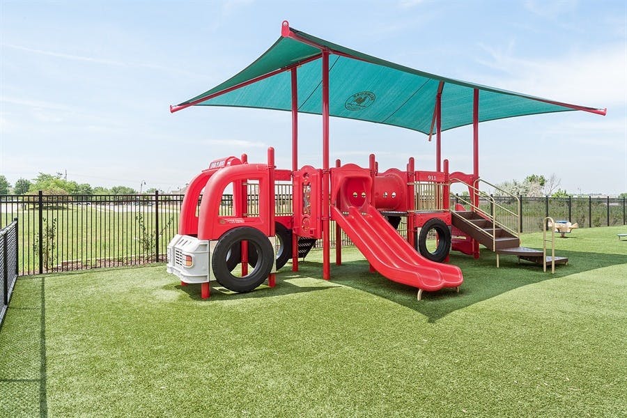 Red playground structure with a slide and a teal shade canopy
