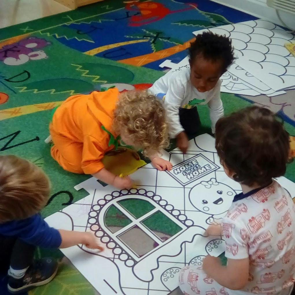 Children coloring a large drawing on the floor