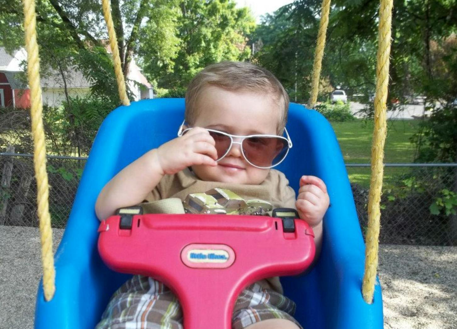 Child in a swing wearing sunglasses