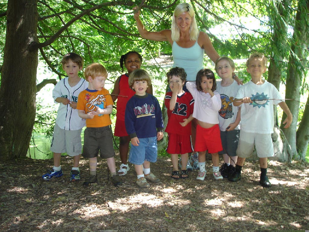 Adult and group of children standing outdoors