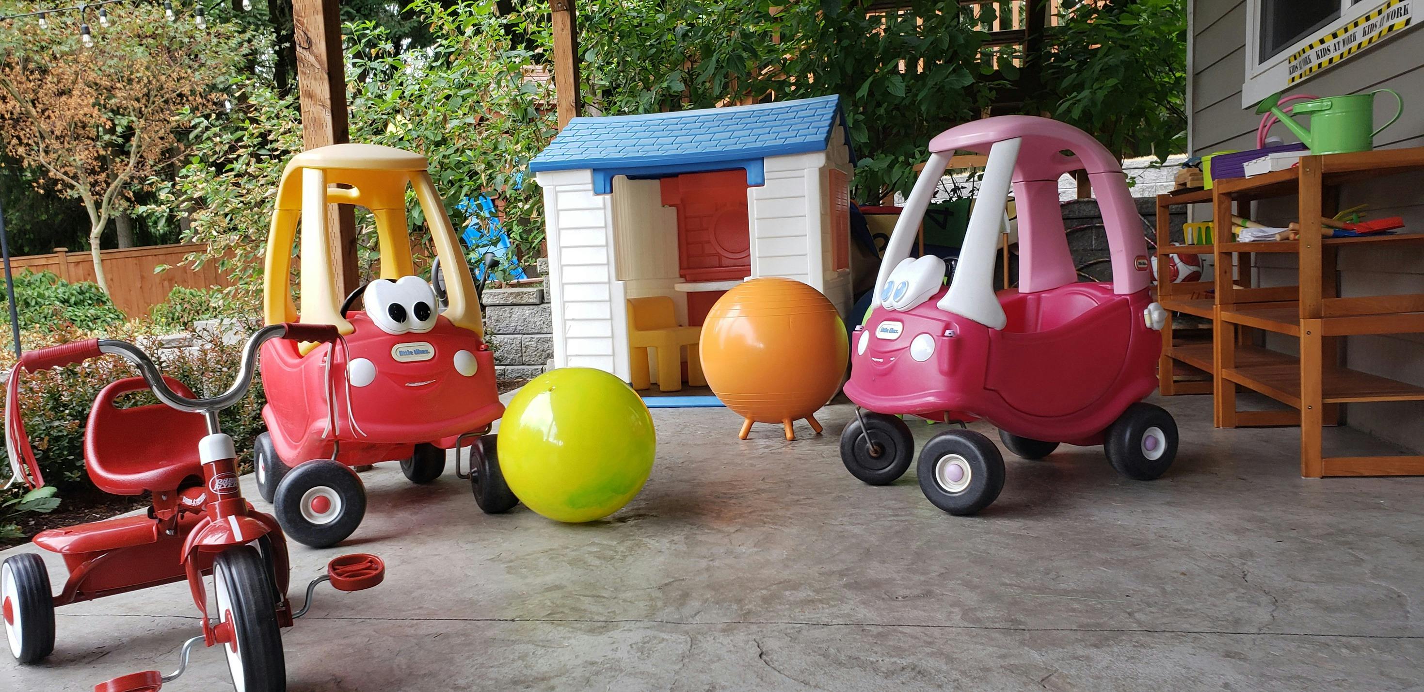 Children's play area with toy cars, tricycle, playhouse, and balls