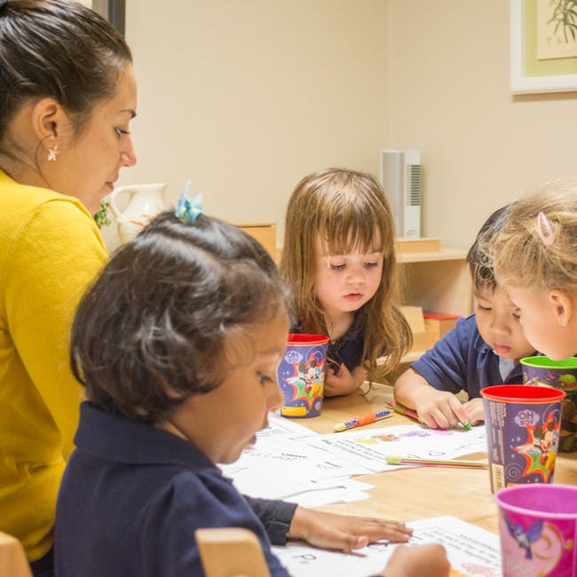 Adult and multiple children drawing at a table