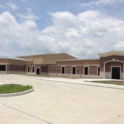 Exterior of a brick building with a paved driveway and grassy area
