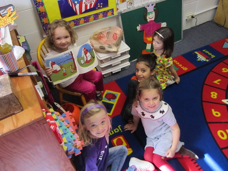Children in a classroom, one child reading a book