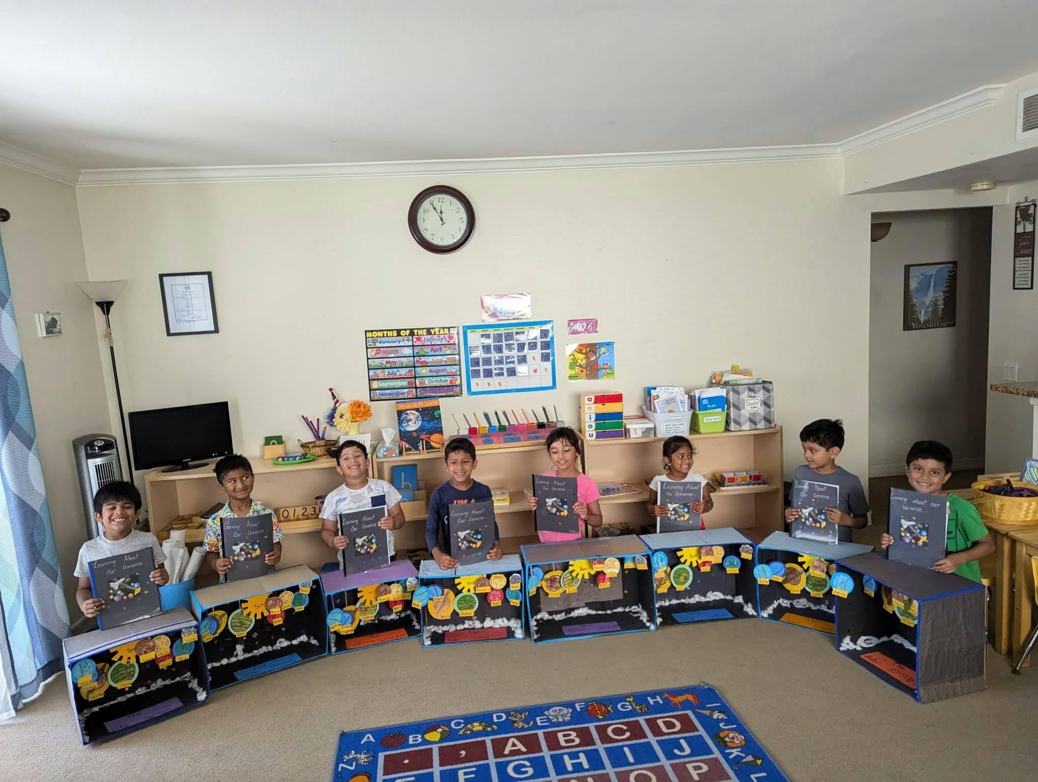 Children sitting at desks holding books in a classroom