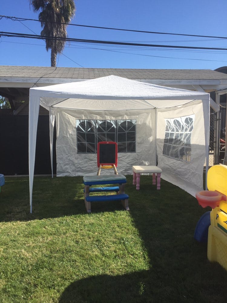 White canopy tent with a small chalkboard and child-sized furniture on grass
