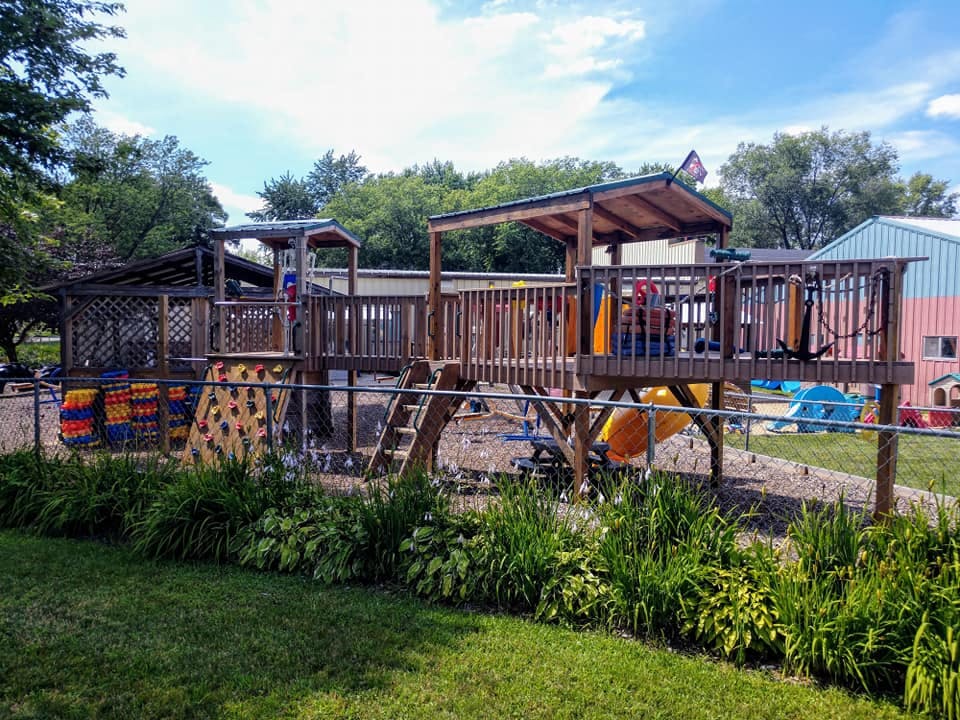 Wooden playground structure with slides and climbing wall