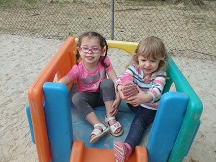 Two children sitting on a colorful plastic play structure