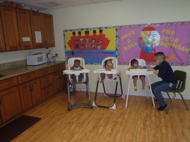 Adult feeding children in high chairs