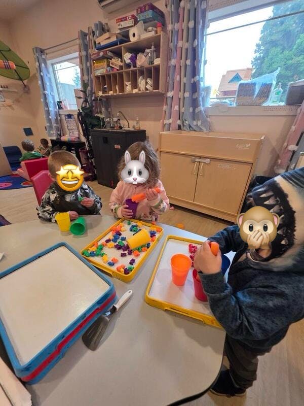 Three children playing with colorful objects at a table
