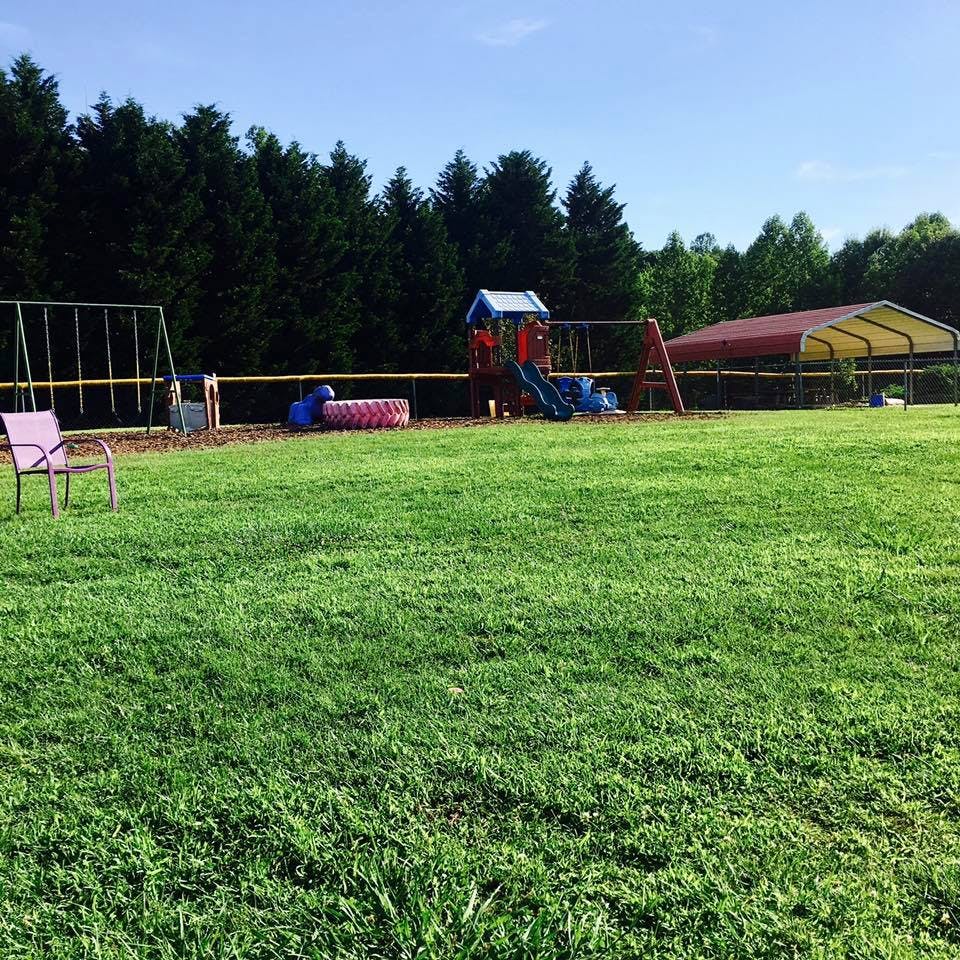 Playground with swings, slide, and covered structure on a grassy field
