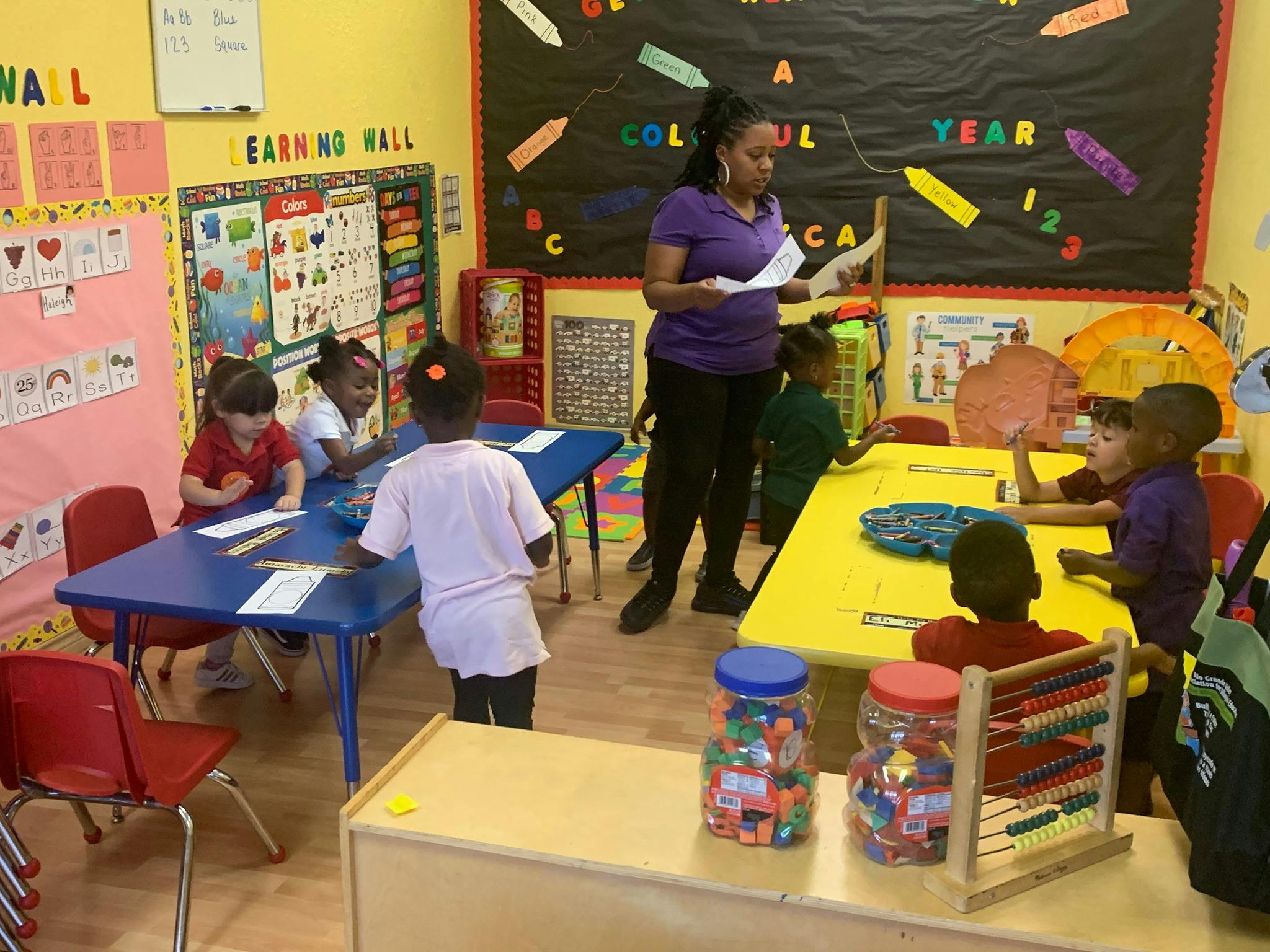 Adult person standing in a classroom with children at tables
