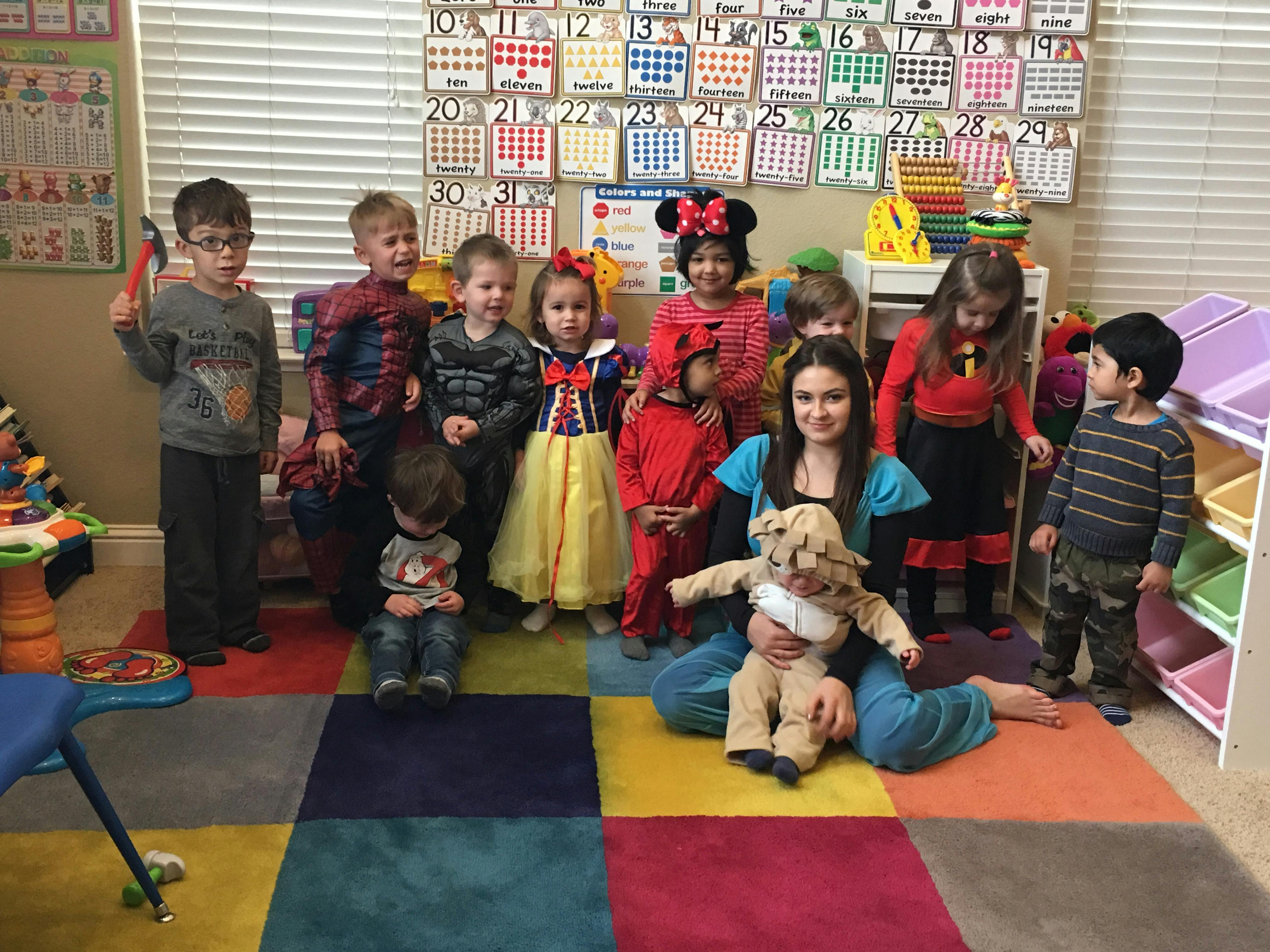 Person sitting on floor with a group of children in costumes