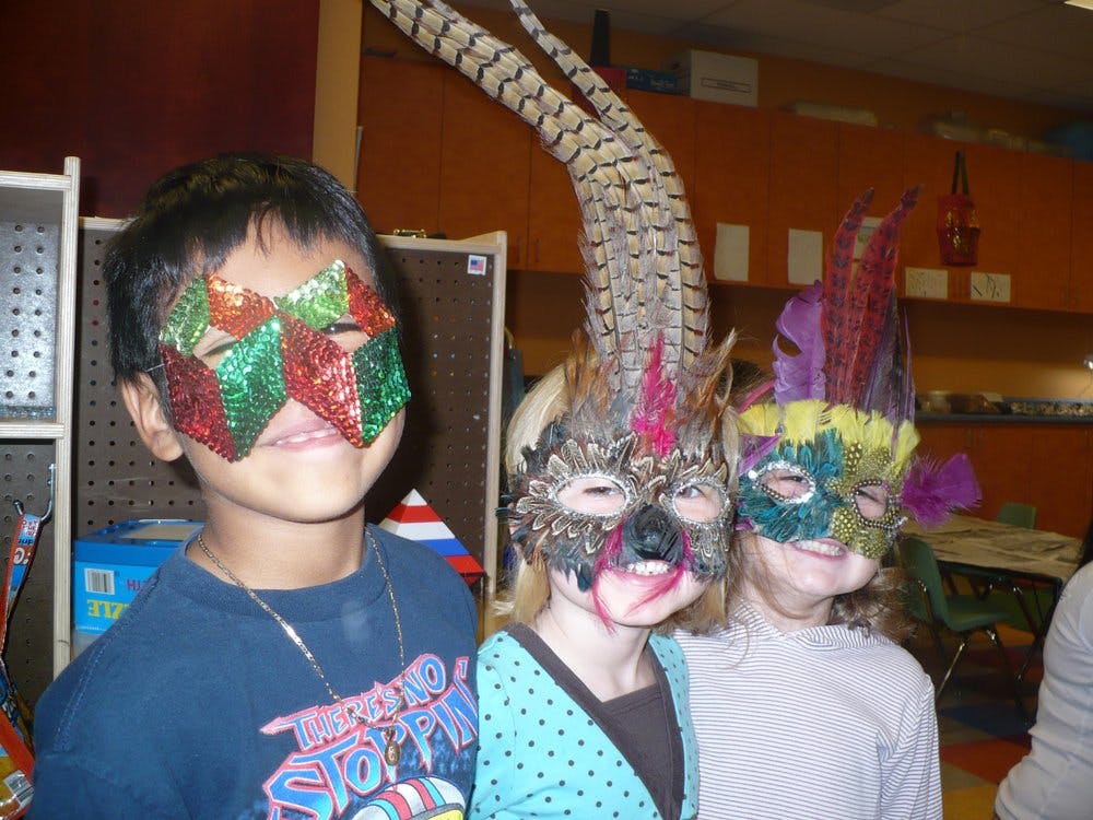 Three children wearing decorative masks