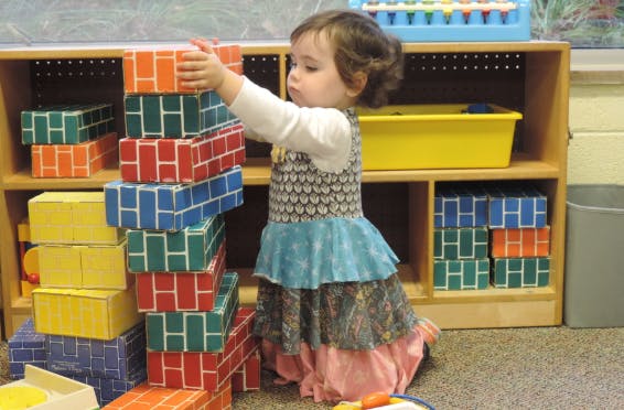 Child stacking colorful blocks in a classroom