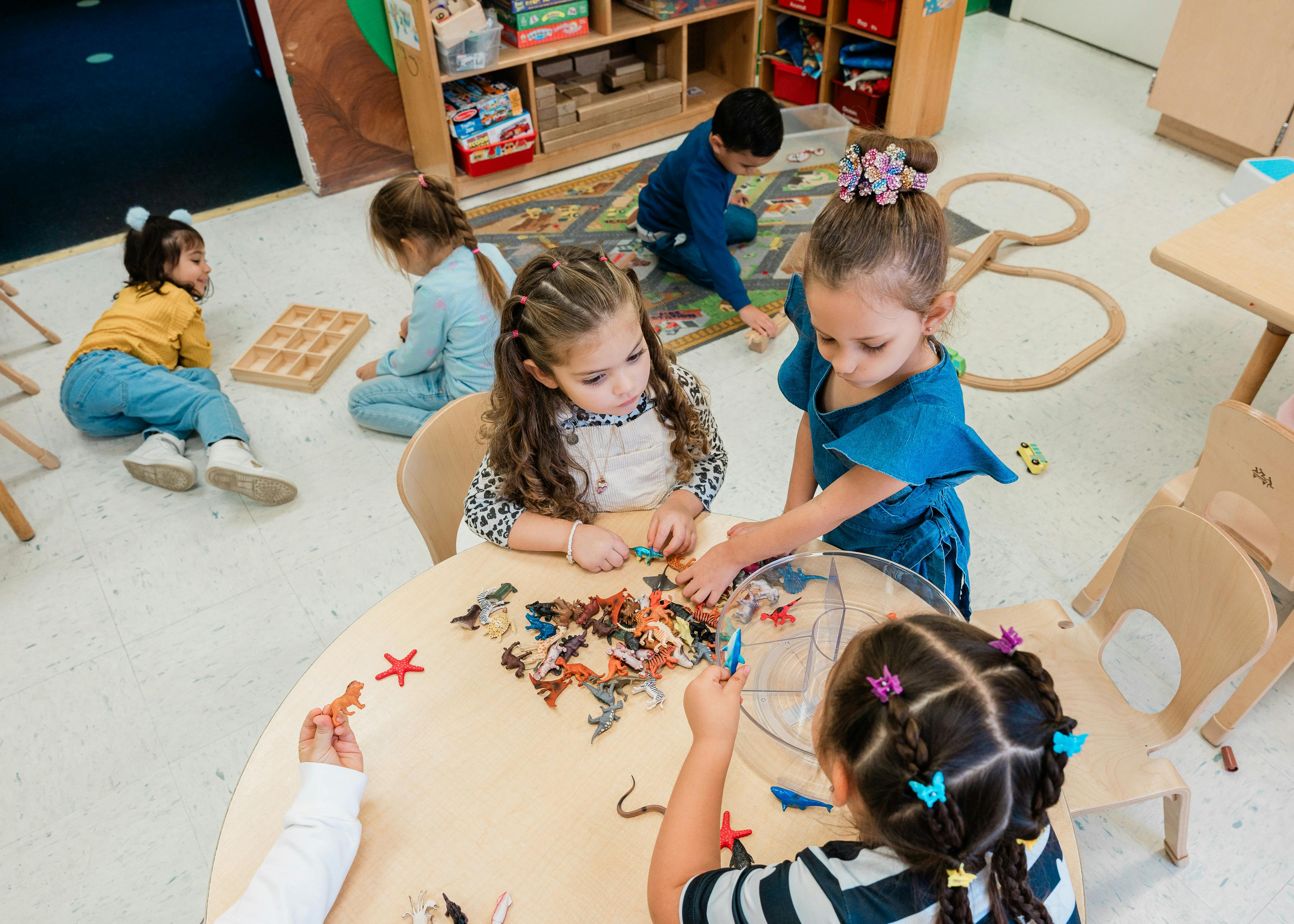 Children playing with toys at a table and on the floor in a classroom
