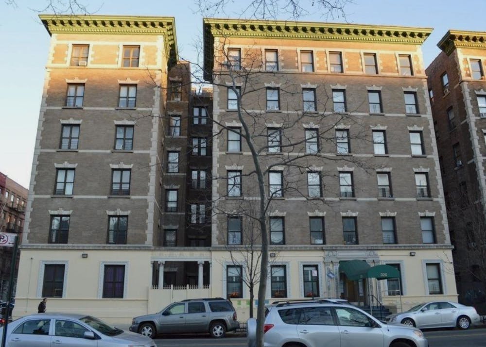 Two tall apartment buildings with cars parked in front