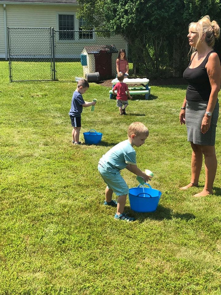 Adult and children playing with water in buckets outdoors