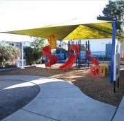 Playground with red slides and yellow shade structure