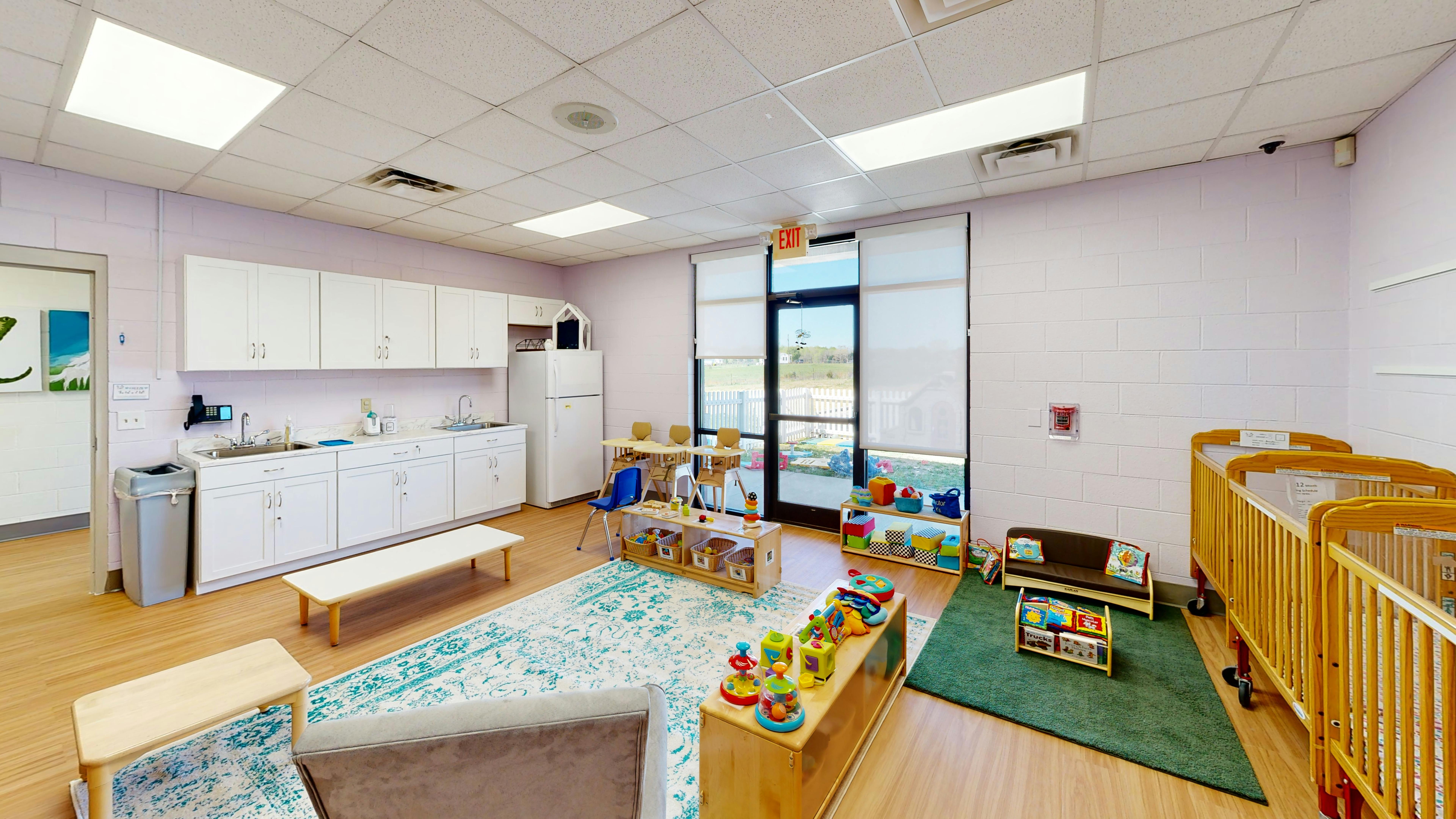 Nursery room with cribs, play area, and kitchen counter