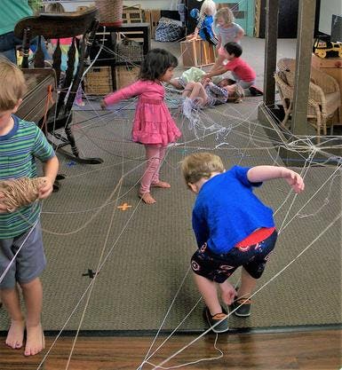 Children playing with string in a room