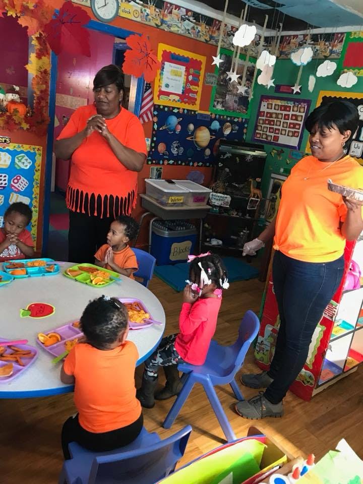 Two people and multiple children in a classroom