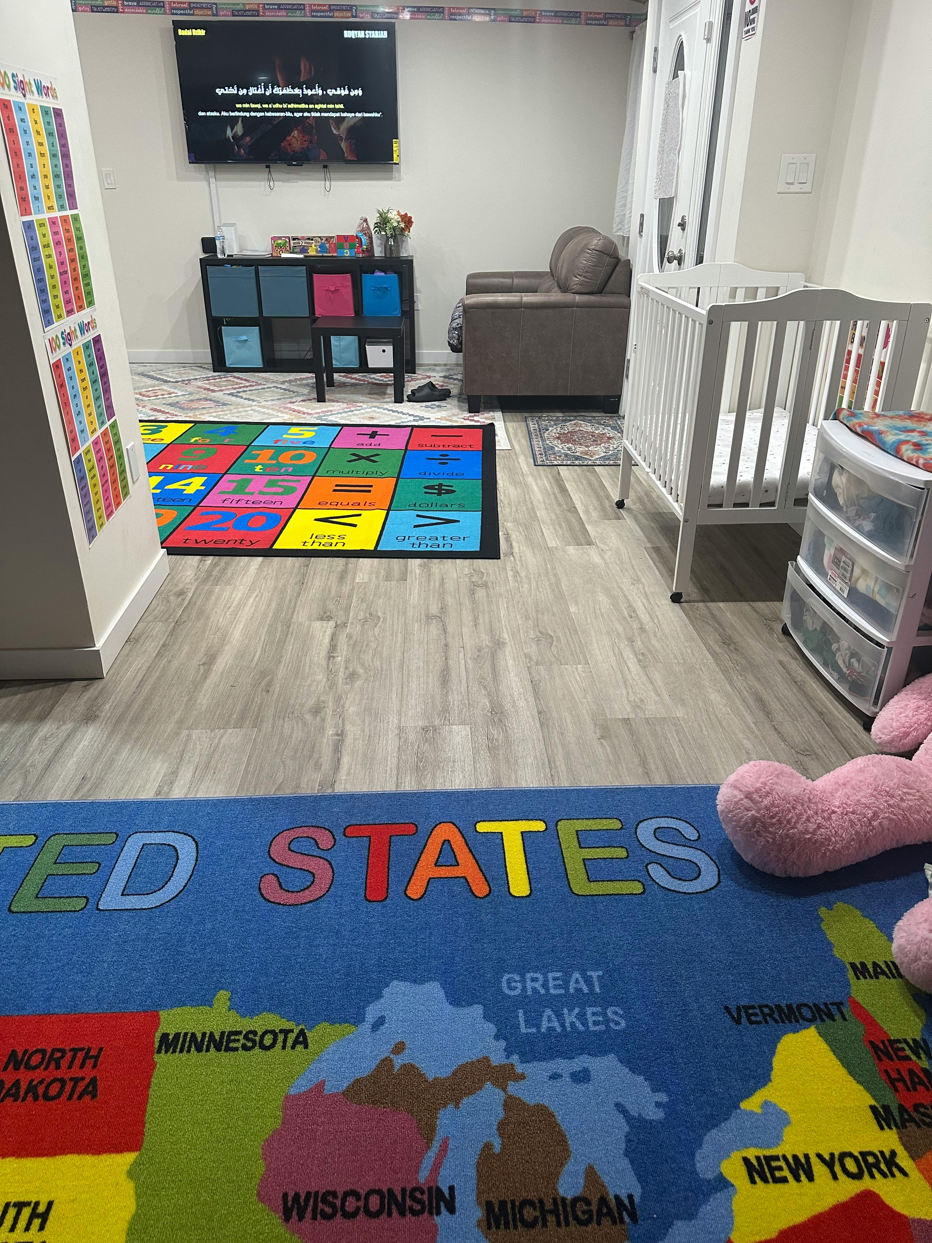 Playroom with a crib, television, and two colorful rugs on the floor